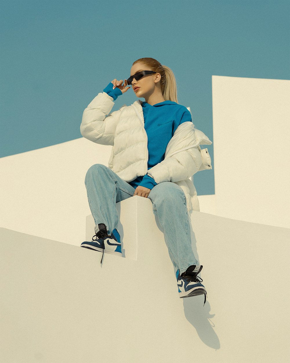 a woman sitting on top of a white wall