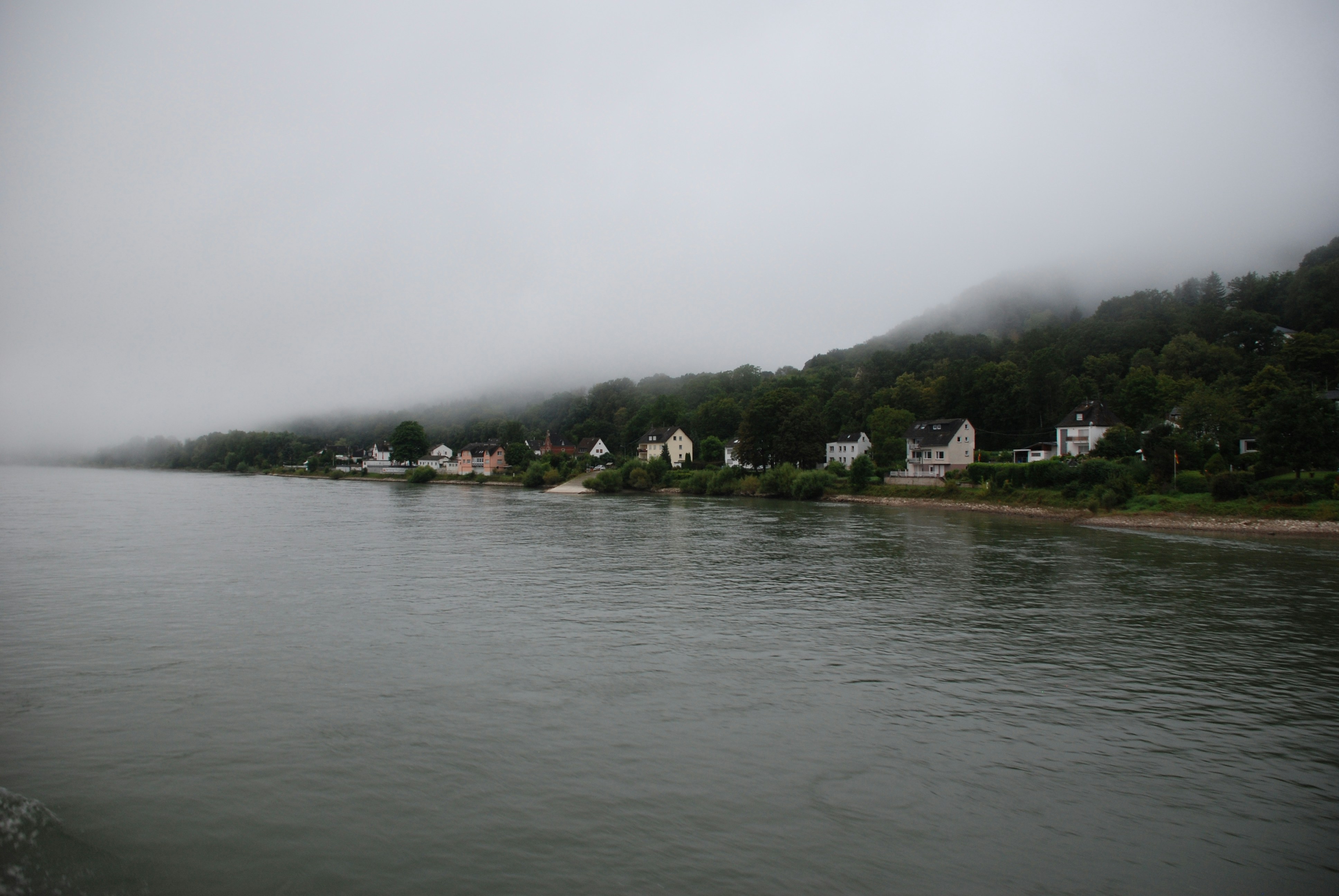 Ein Gewässer mit Häusern auf einem Hügel im Hintergrund