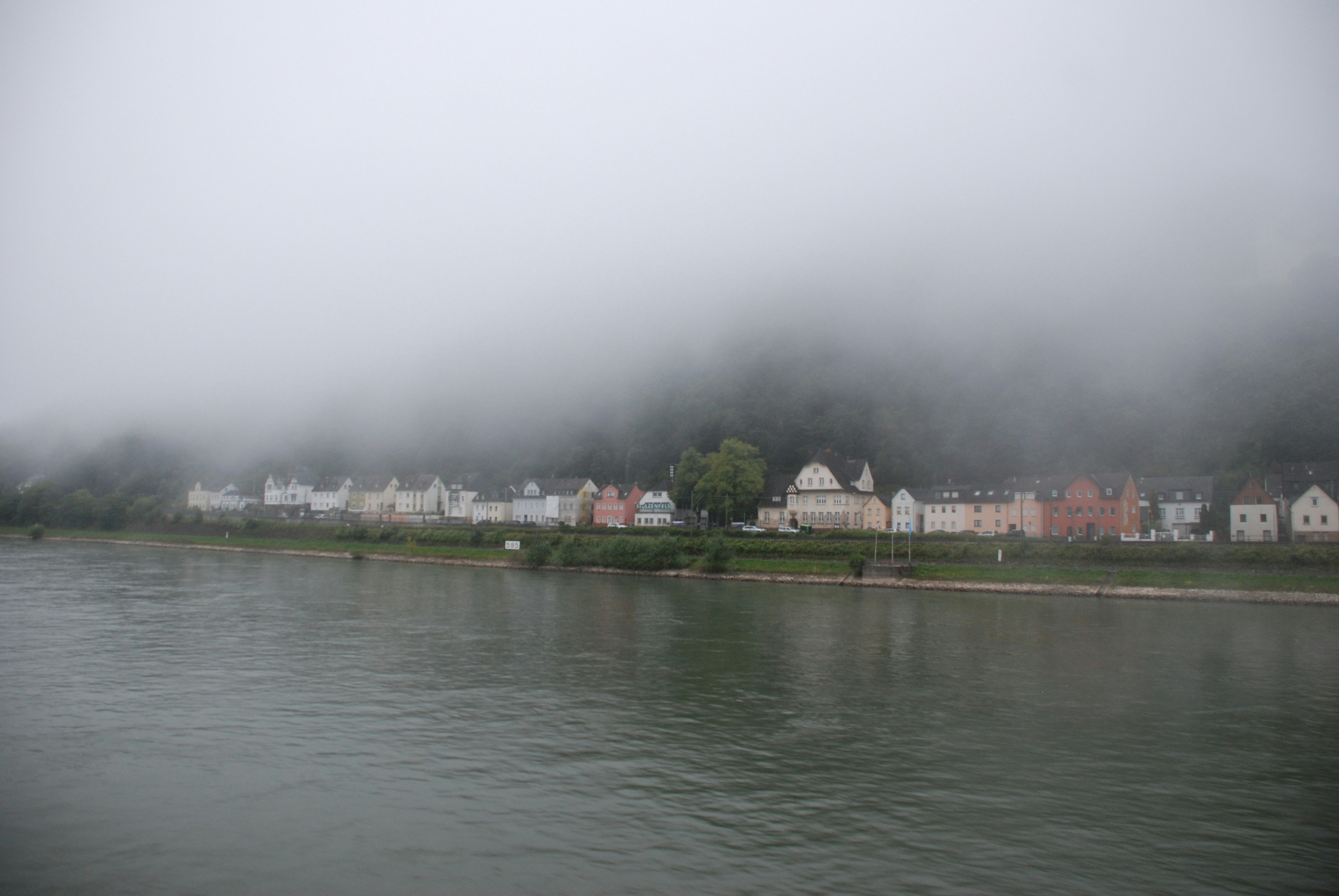 Ein Gewässer mit Häusern auf einem Hügel im Hintergrund