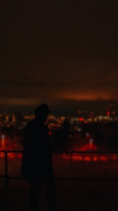 A silhouette of a tall figure blending into a bustling city crowd under a twilight sky.