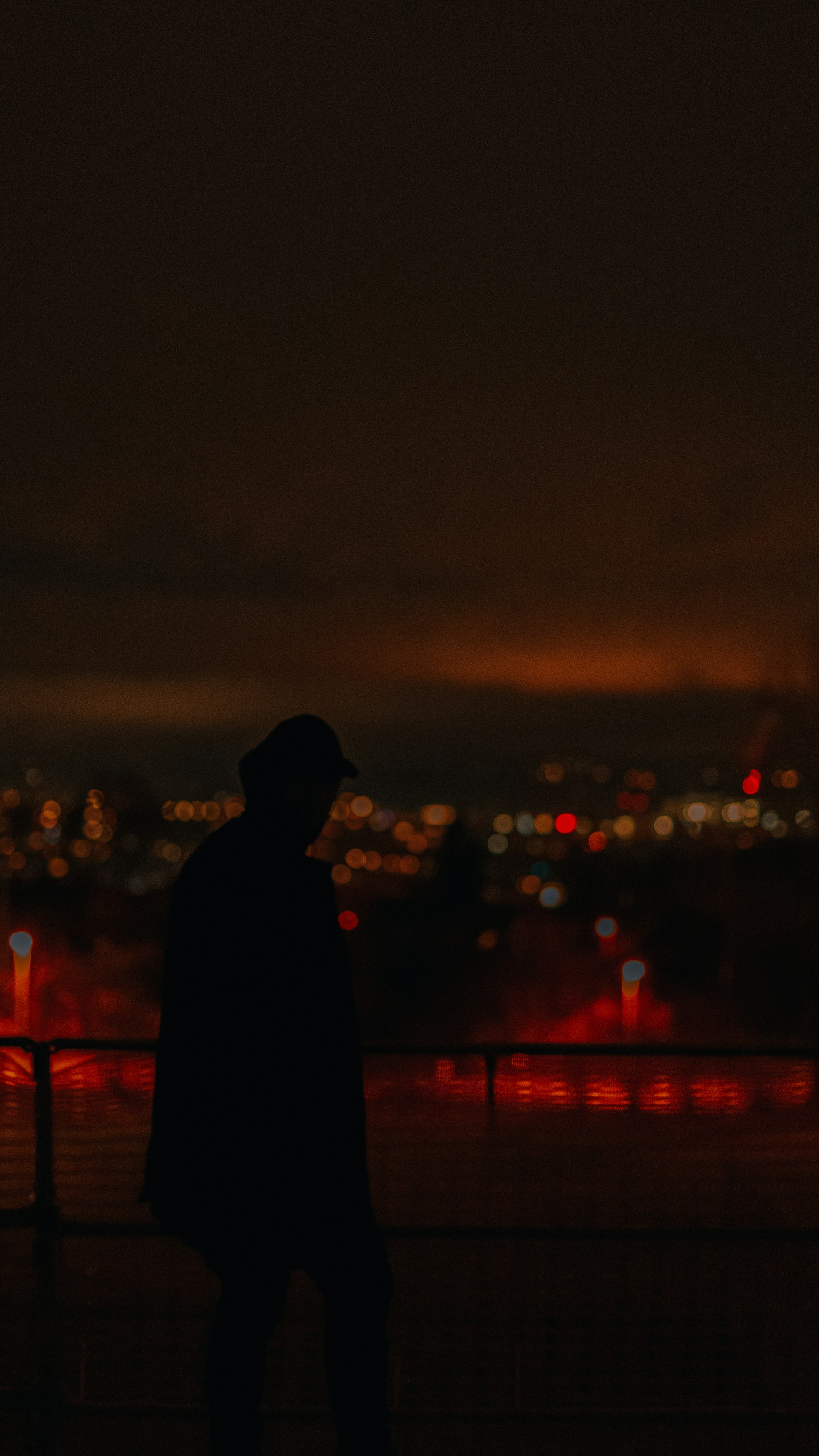 A moody, neon-lit frame from a music video featuring a silhouette against a pulsating cityscape at night.
