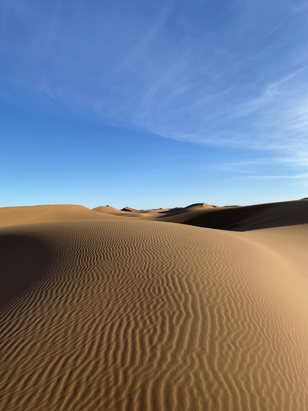 a desert landscape with sand dunes and a blue sky