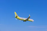 A colorful cartoon airplane soaring above fluffy clouds with kids watching excitedly.