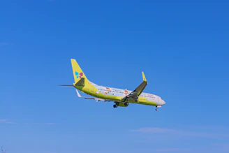 A colorful airplane soaring above fluffy clouds with a child watching excitedly from below