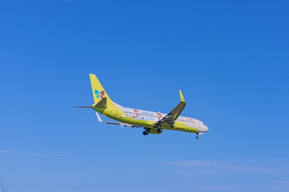 A colorful airplane soaring above fluffy clouds with a child watching excitedly from below