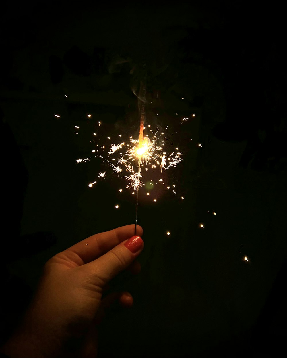 a hand holding a sparkler in the dark