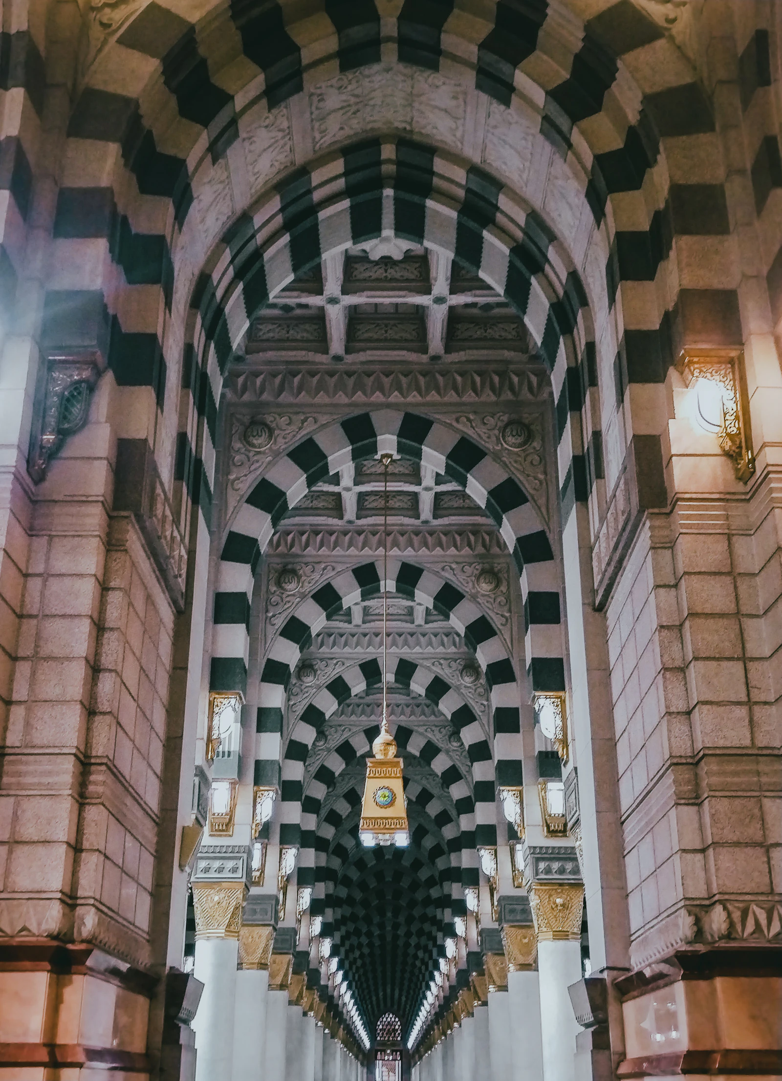 Striped stone arches frame a long, quiet prayer hall.