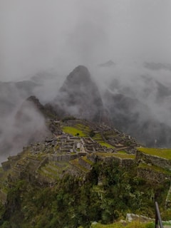 a cloudy view of a mountain with a village on top of it