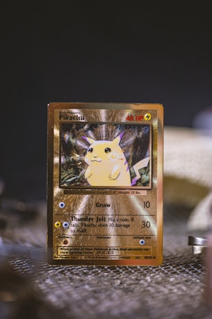 A shiny collectible card featuring a yellow fictional creature with pointed ears and a friendly expression. The card has a golden border and displays various statistics and attack details. The background is slightly blurred, emphasizing the card in the foreground.