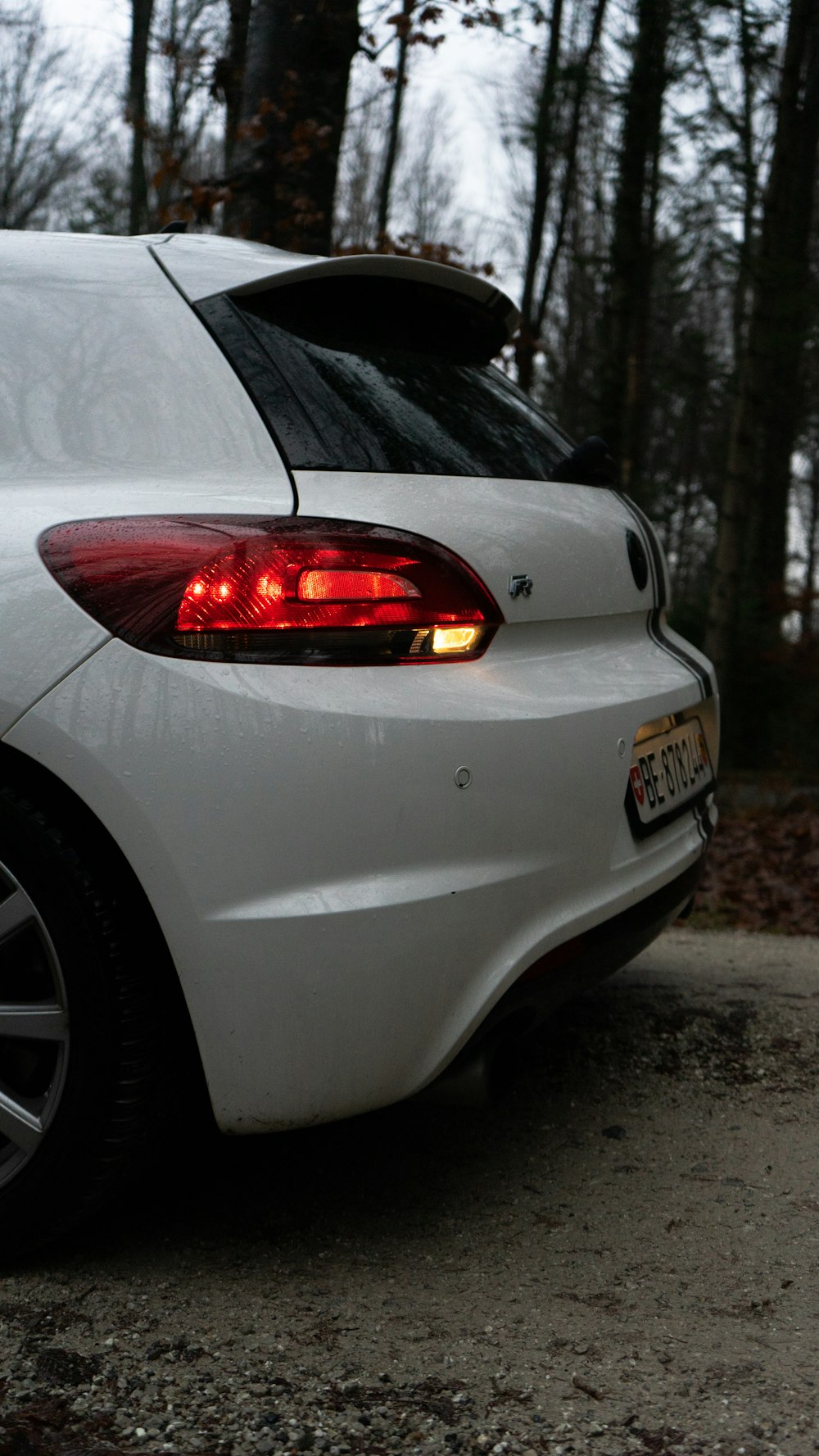 a white car parked in front of a forest