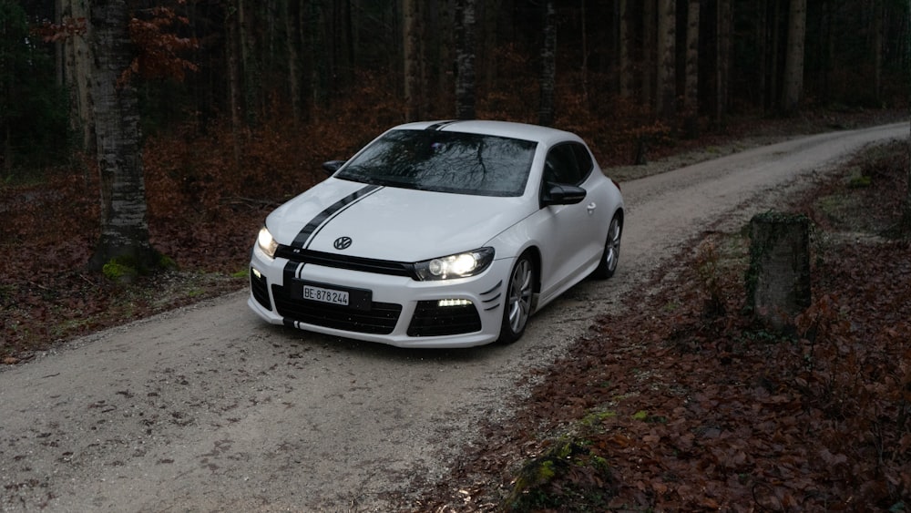 a white car parked on a dirt road in the woods