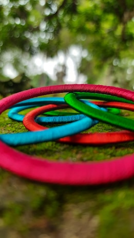 A collection of colorful glass bead rings arranged on a bed of soft green moss.