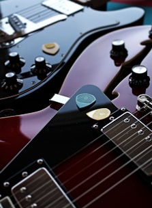 Close-up of two guitars leaning against each other beside a microphone.