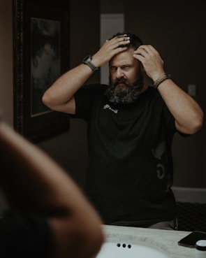 a man with a beard standing in front of a mirror