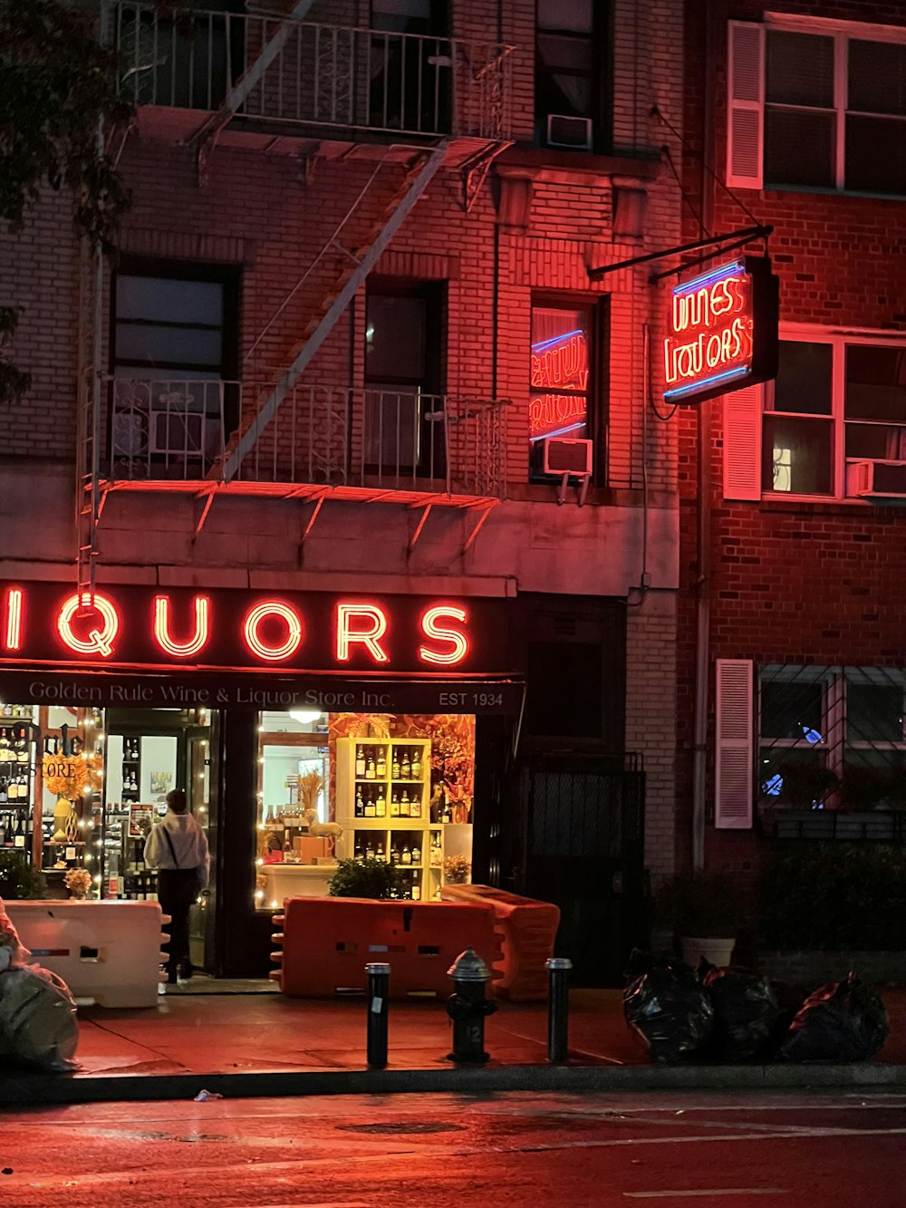a red neon sign that reads liquors on the side of a building