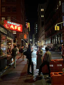 A neon-lit urban street corner at night with a group of friends enjoying cold drinks.