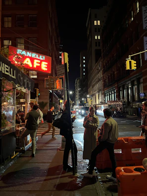A neon-lit urban street corner at night with a group of friends enjoying cold drinks.