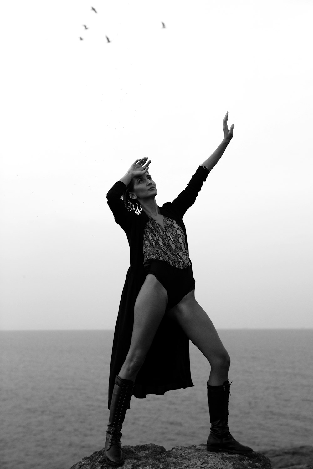 a woman standing on top of a rock near the ocean