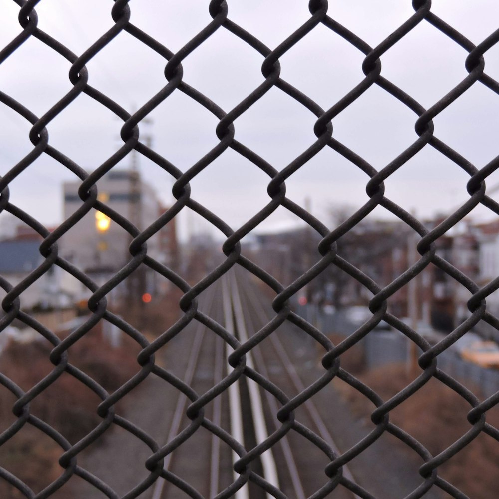 Una vista de una vía de tren a través de una cerca de alambre