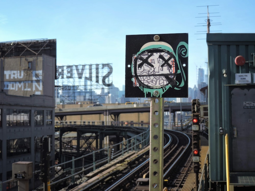 a street sign on a pole in front of a train track