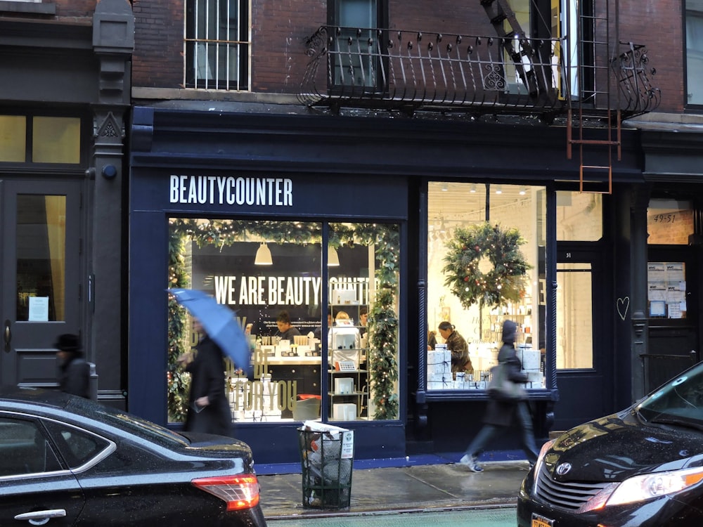 a woman walking down a street past a beauty counter