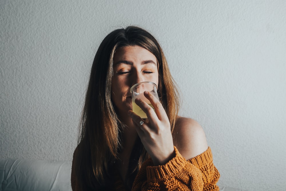 a woman drinking a glass of water on a couch