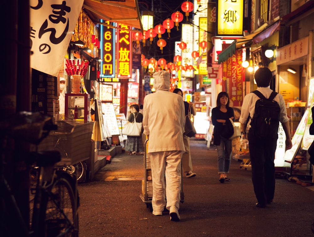 a group of people walking down a street at night