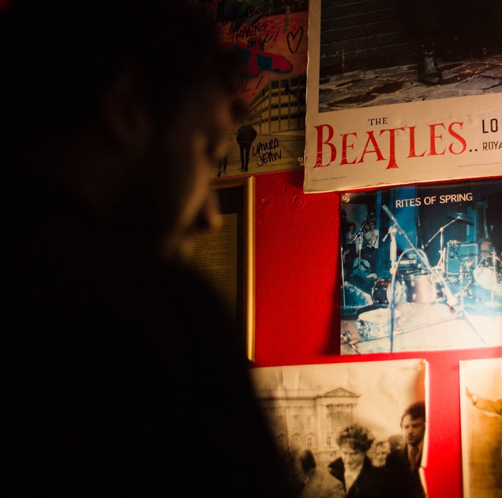 a man standing in front of a wall with posters on it