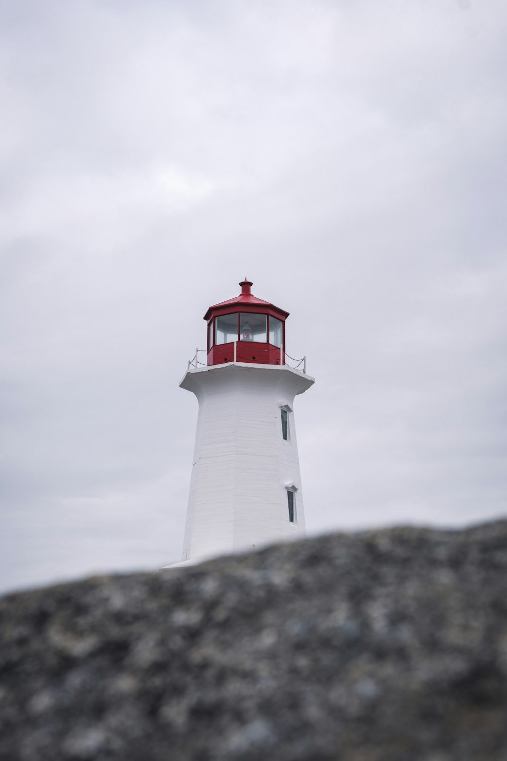 a red and white lighthouse on a cloudy day