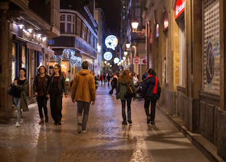 A lively street scene in Reims at night with people using their smartphones.