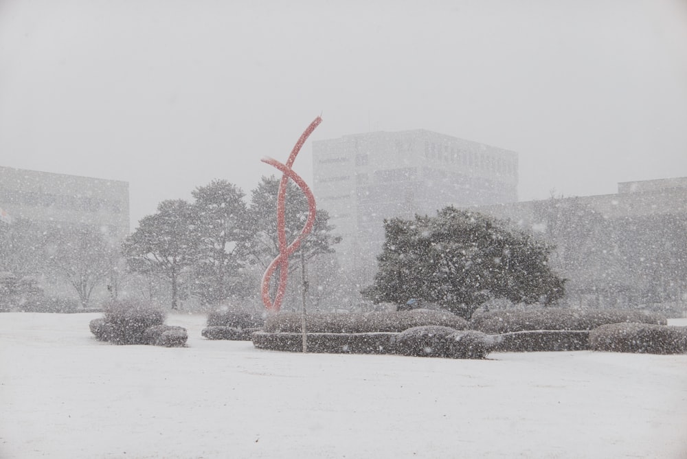 a snowy day in a city park with a red sculpture