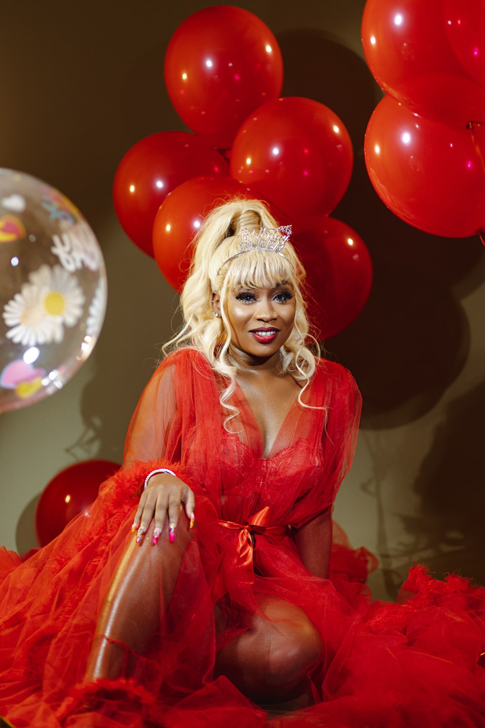 a woman in a red dress sitting in front of balloons