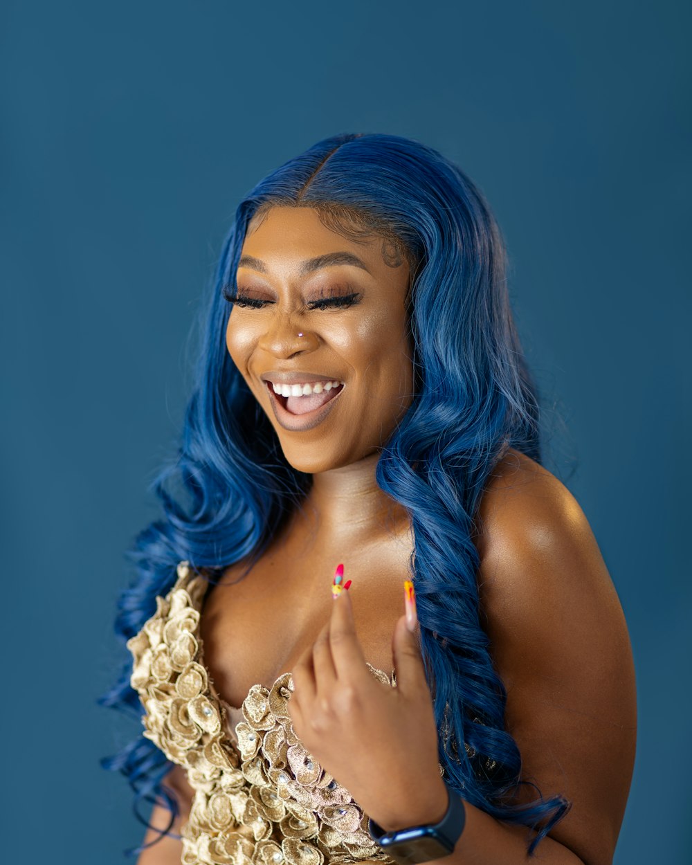 a woman with blue hair smiling and wearing a gold dress