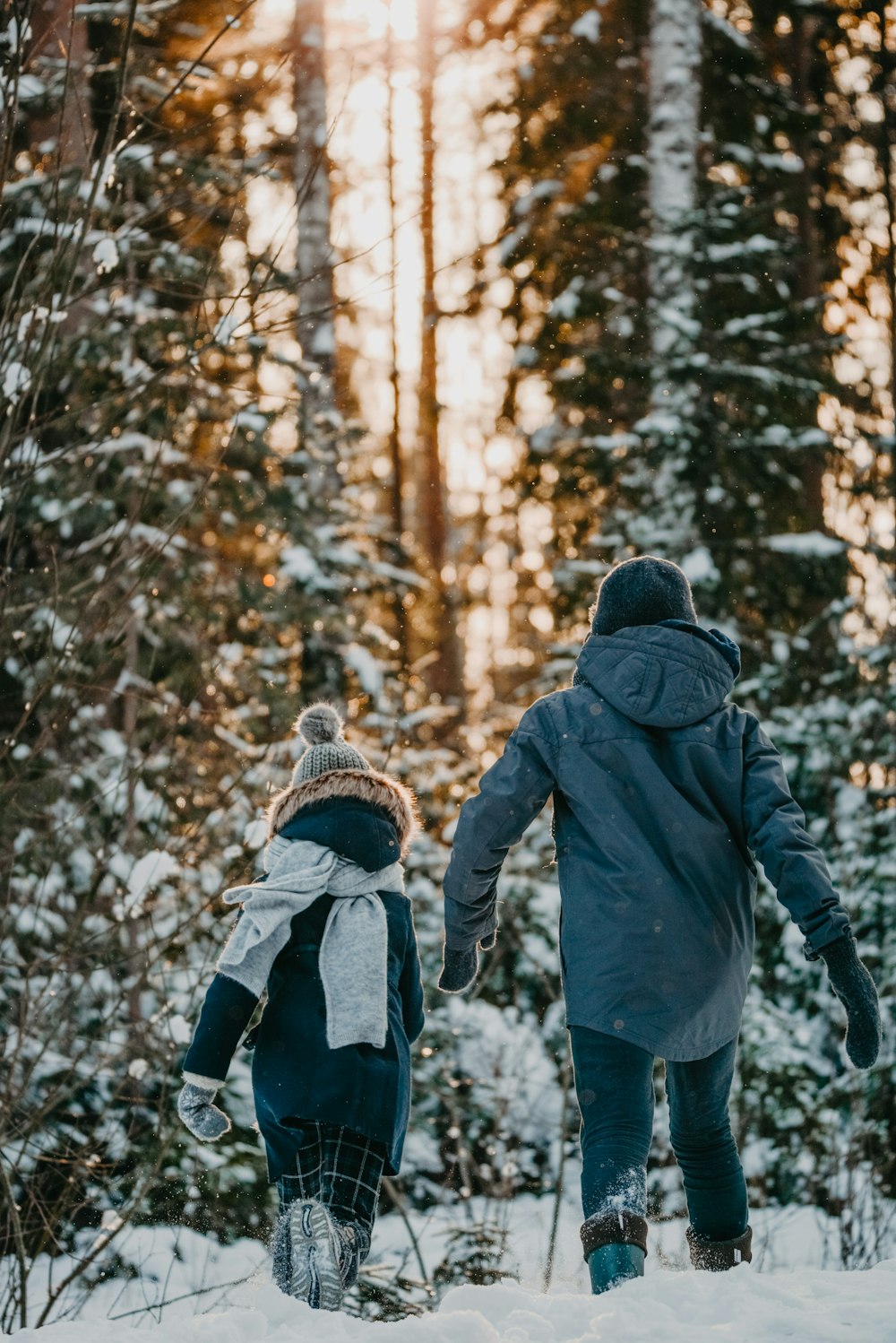 a couple of people walking through a snow covered forest