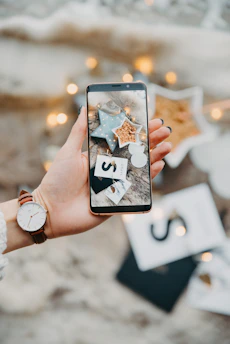 Close-up of hands holding a smartphone showing a bright and festive invitation design.