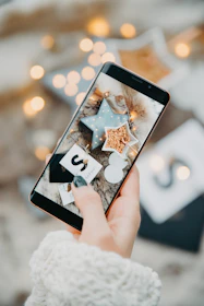 a person holding a cell phone with a christmas decoration on it