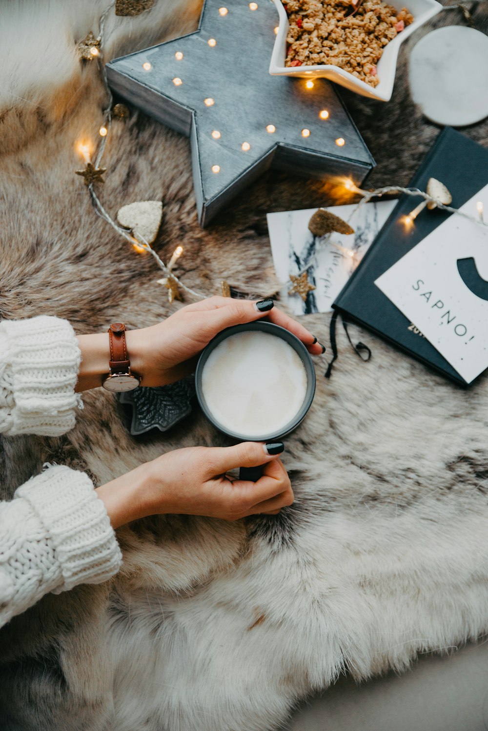 a woman holding a cup of coffee on top of a furry rug