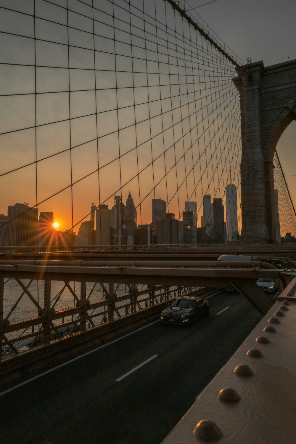 the sun is setting over the brooklyn bridge