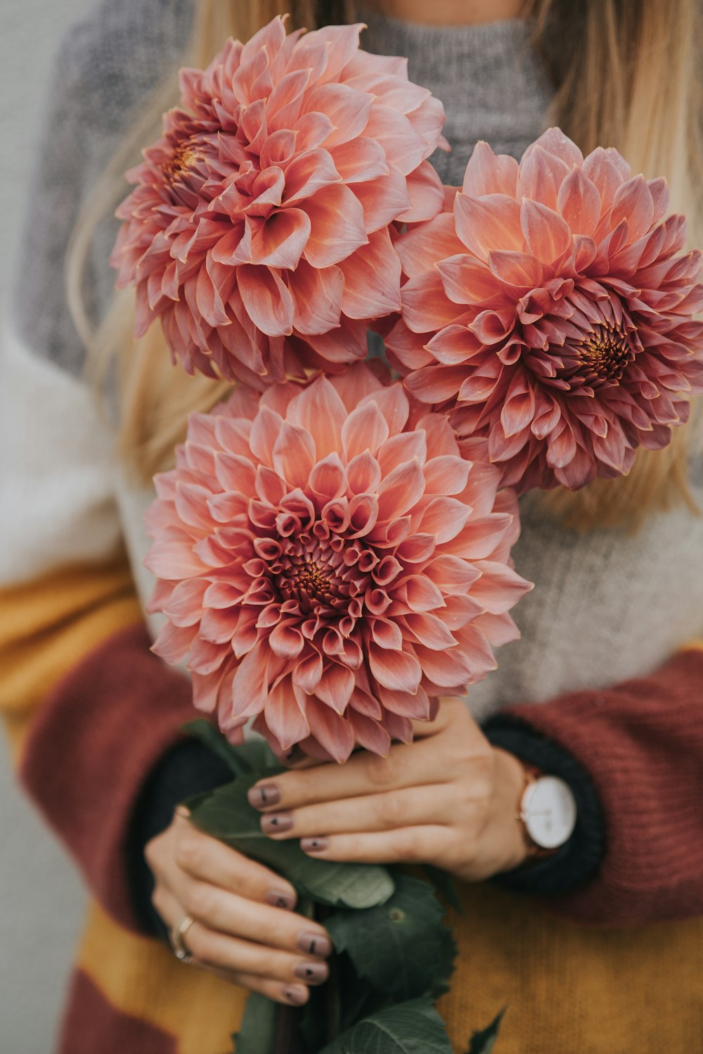 a woman holding a bunch of pink flowers