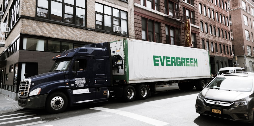 a semi truck driving down a street next to tall buildings