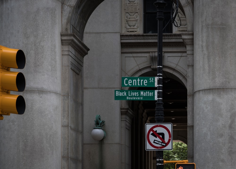 a couple of green street signs hanging from the side of a building