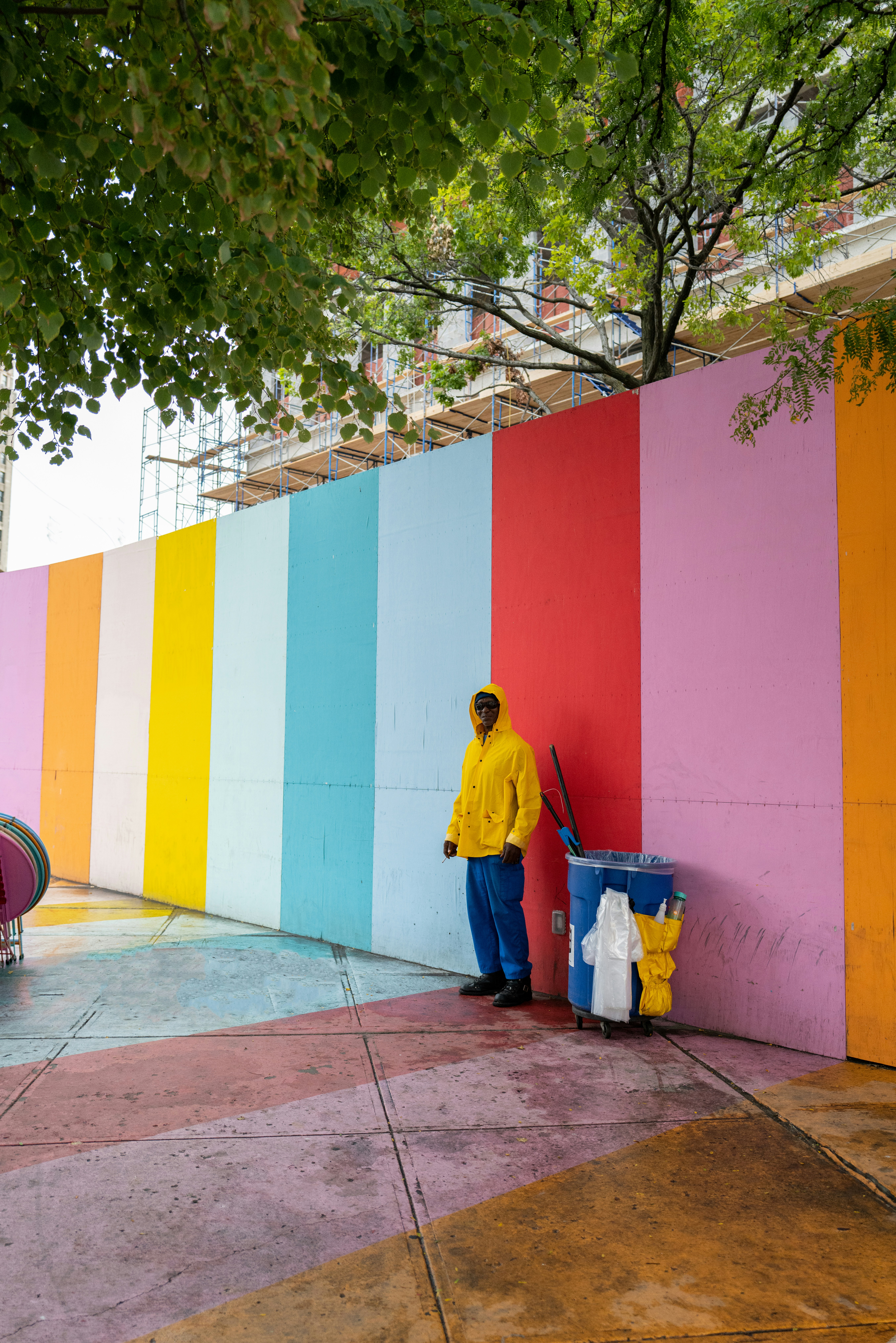 a man standing next to a rainbow colored wall