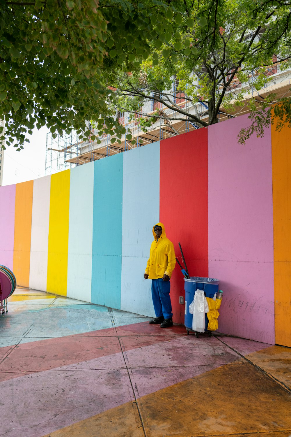 a man standing next to a rainbow colored wall