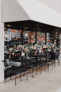 tables and chairs outside of a flower shop