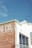 A corner of a building with a partially visible sign that reads 'G CO.' on a weathered brick wall, next to a white section with a large window reflecting the sky. The rooftop features decorative edges and the number 315 is visible.