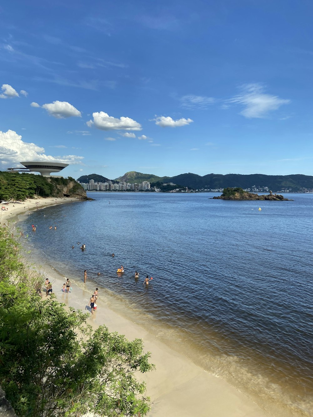 a group of people standing on top of a beach next to a body of water