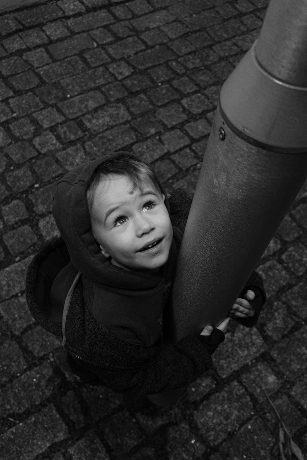 a little boy that is standing next to a pole