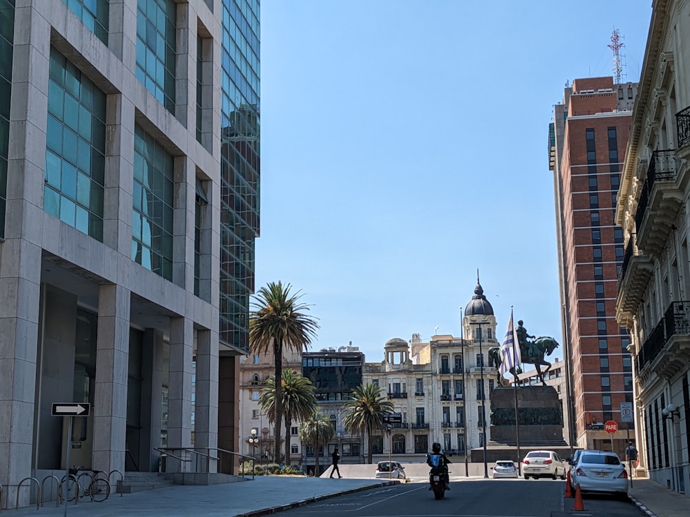 a man riding a bike down a street next to tall buildings