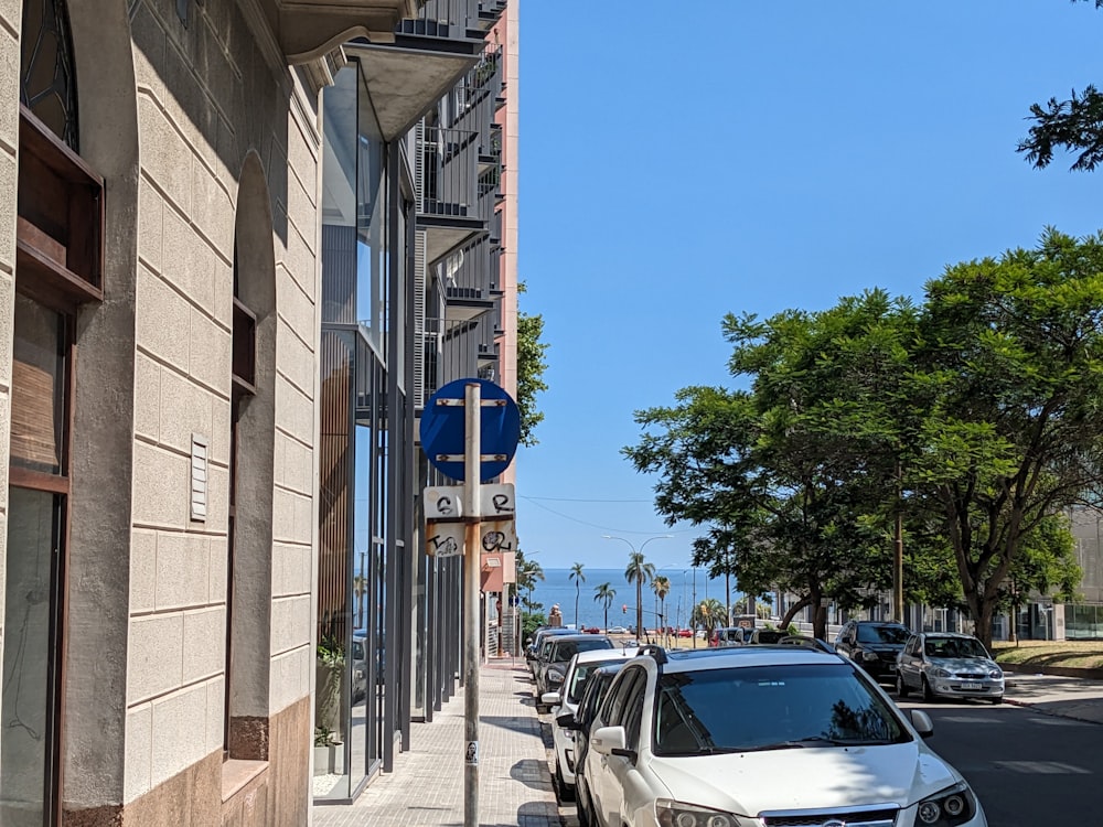 cars parked on the side of a street next to a tall building