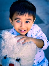 A cheerful child hugging a large stuffed bear in a sunlit room.